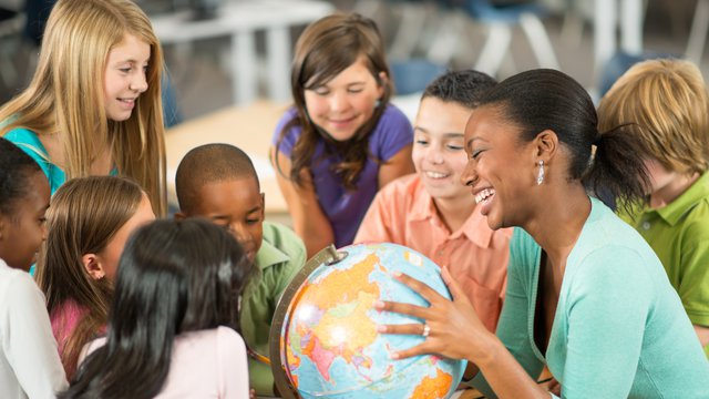 Students and teacher looking at globe